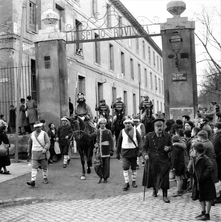 La Cabalgata de los Reyes Magos por Zaragoza en 1939. Imagen capturada durante la "cabalgata de los Reyes Magos" celebrada el 5 de enero de 1939, con salida en la plaza de Santo Domingo frente el Ayuntamiento y regreso al mismo punto tras un largo recorrido urbano donde en la plaza de Basilio Para&iacute;so se les uni&oacute; el "Mago Nicol&aacute;s". En la imagen, la comitiva del rey Gaspar con sus pajes a caballo y criados a su servicio sale de los jardines del Hospicio Provincial entre los asilados del Hogar Pignatelli para seguir su itinerario por la calle de la Madre Rafols / Gran Archivo Zaragoza Antigua