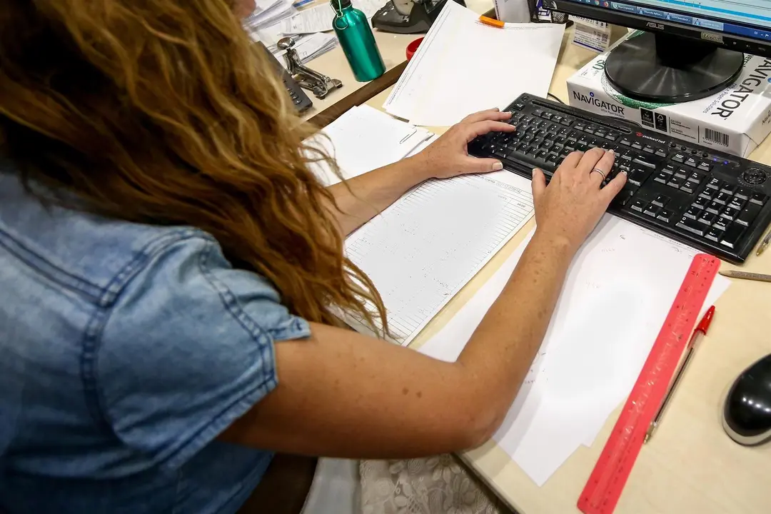 Una mujer escribe en el teclado de su ordenador, con papeles alrededor mientras trabaja en la oficina. / E.P.