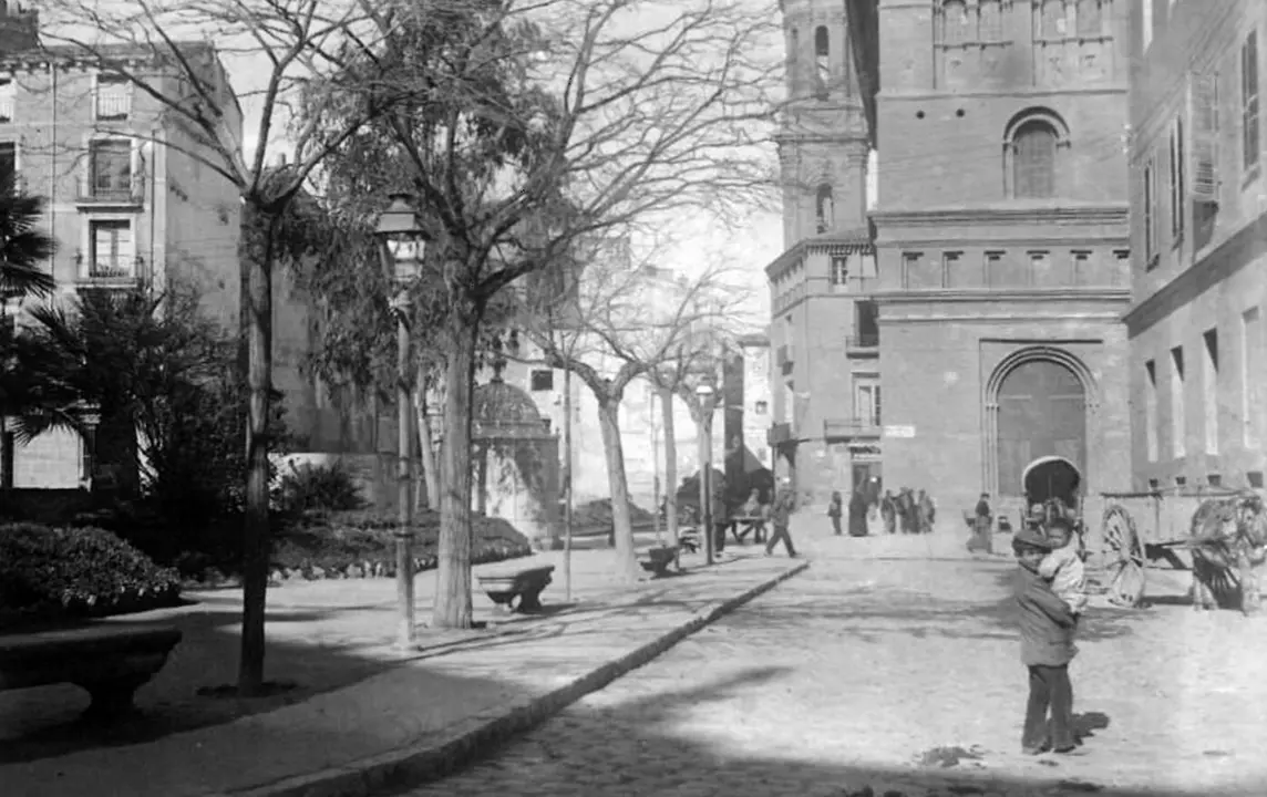 A&ntilde;o 1920. Fotograf&iacute;a capturada en la plaza de La Seo, donde resalta su isla verde coronada por la emblem&aacute;tica Fuente de la Samaritana, junto a la controvertida presencia de un mingitorio que desentona en el entorno. Al fondo, m&aacute;s all&aacute; de la calle Fernando el Cat&oacute;lico, se observa el ensanche de la calle del Pilar / GAZA