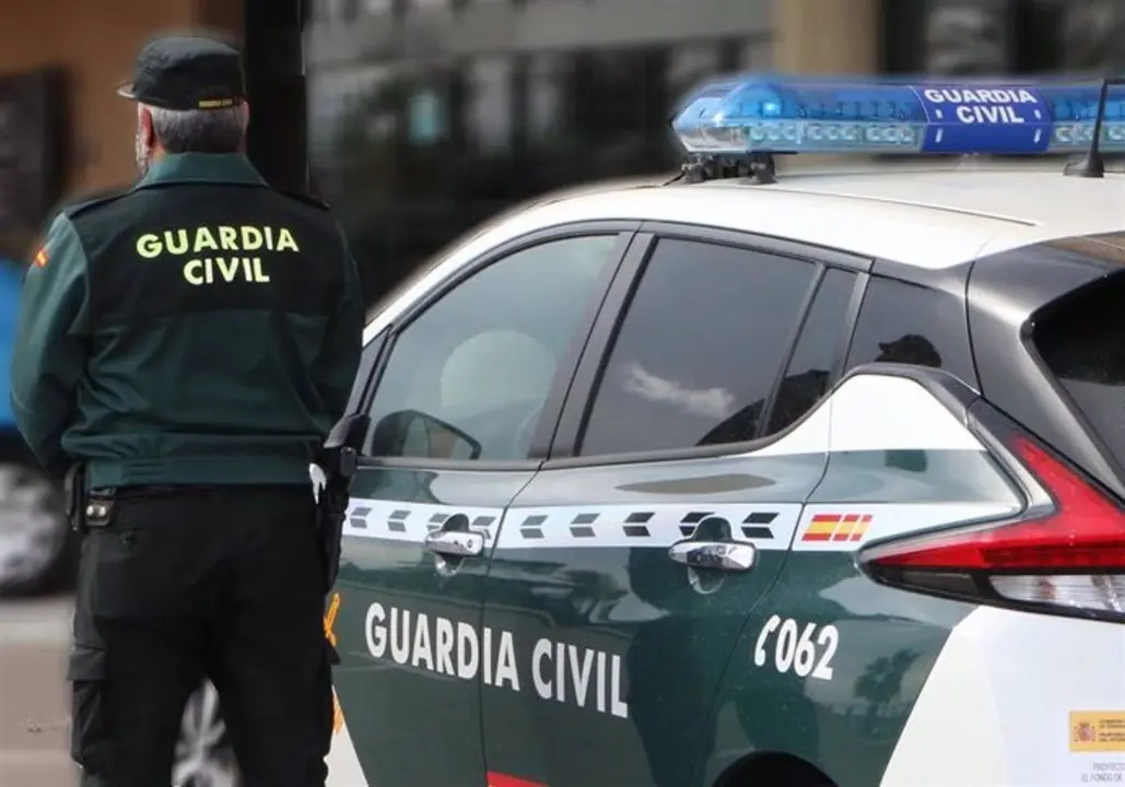 Un agente de la Guardia Civil, de espaldas, junto a un veh&iacute;culo oficial. - GUARDIA CIVIL