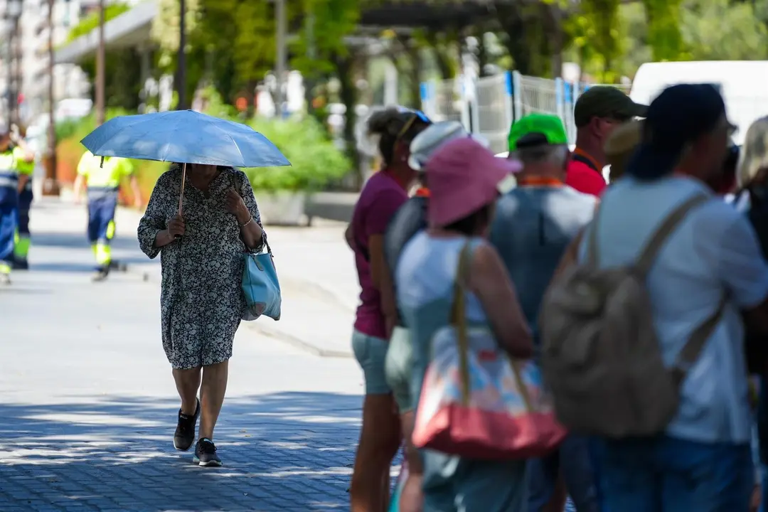Una mujer con una sombrilla junto a un grupo de turistas. /  Europa Press