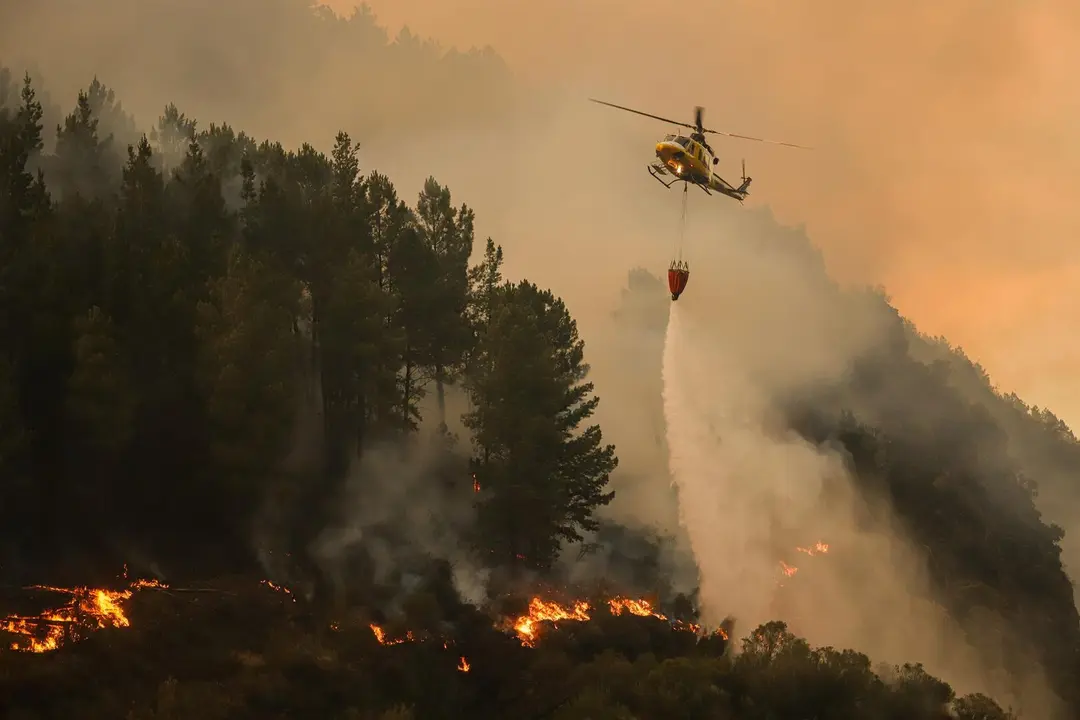 Un helic&oacute;ptero suelta agua sobre el fuego, a 26 de agosto de 2025, en Covas, Lugo. / EP