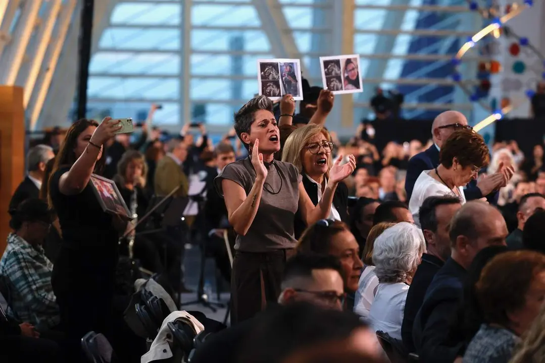Familiares de v&iacute;ctimas de la dana, con fotos de sus allegados, protestan antes del inicio del funeral de Estado. / EP