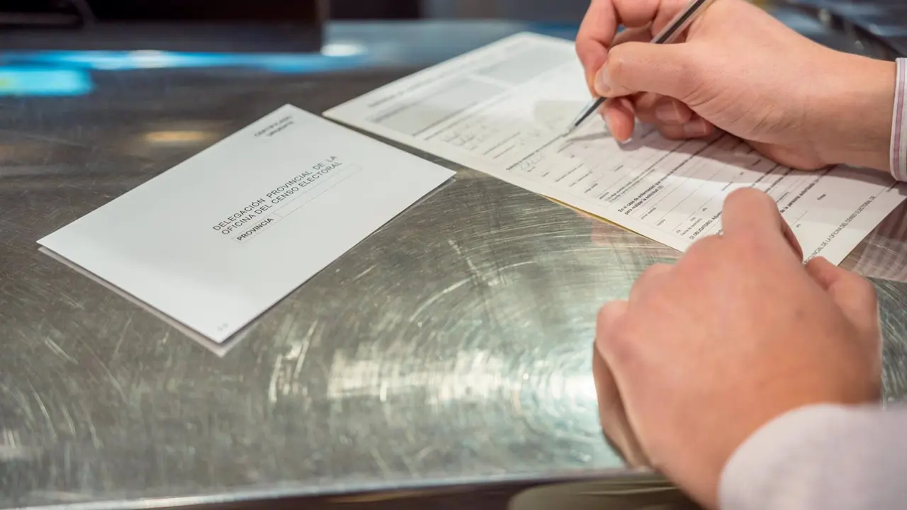 Una persona rellena unos documentos tras solicitar el voto por correo en el Edificio de correos / EP