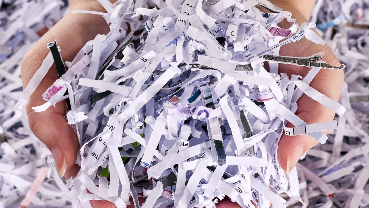 Studio shot of a womans hands holding a pile of shredded paper.