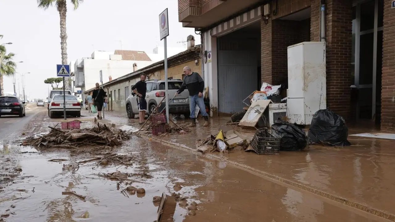 Varias personas limpian el lodo acumulado en sus viviendas a causa de las intensas lluvias en Valencia / EFE