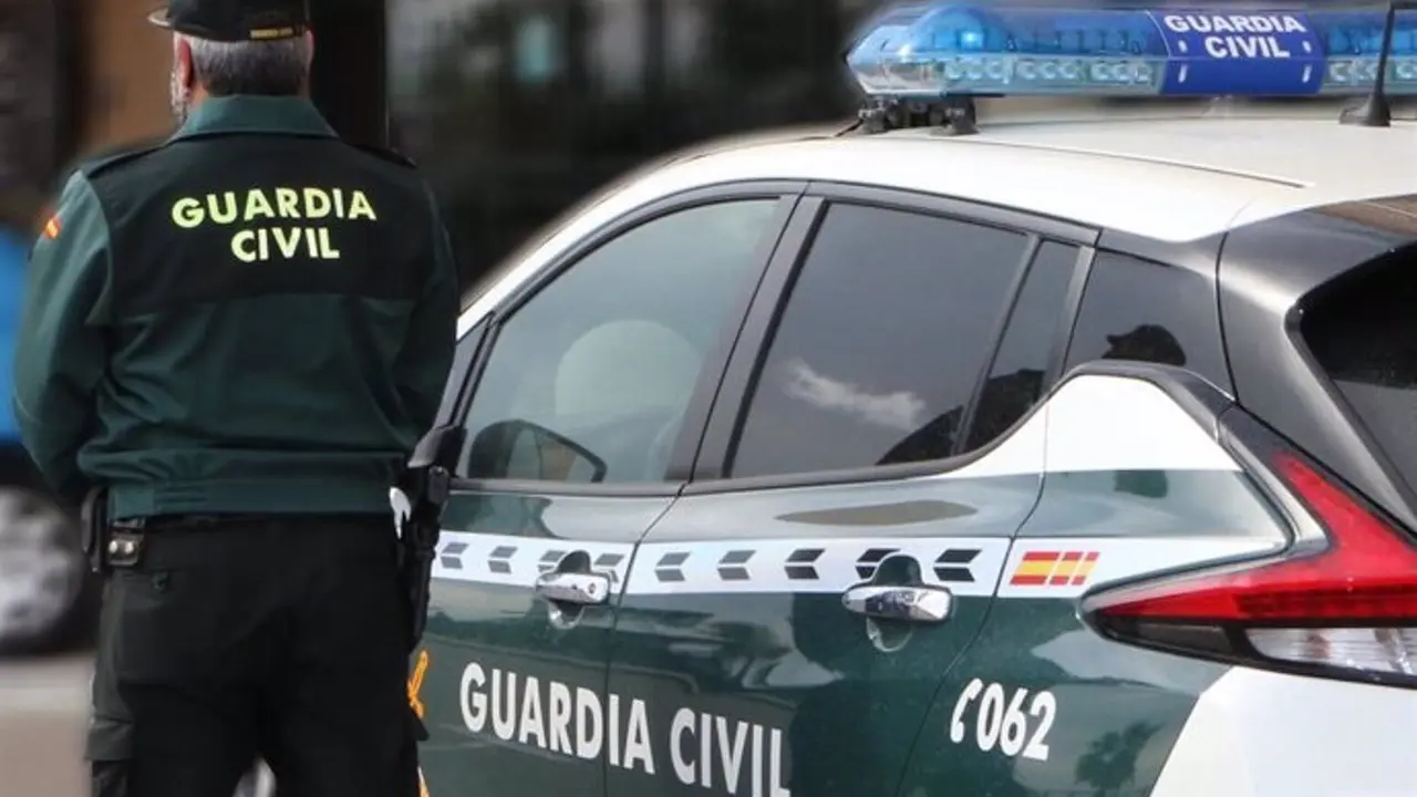 Un agente de la Guardia Civil, de espaldas, junto a un veh&iacute;culo oficial. - GUARDIA CIVIL