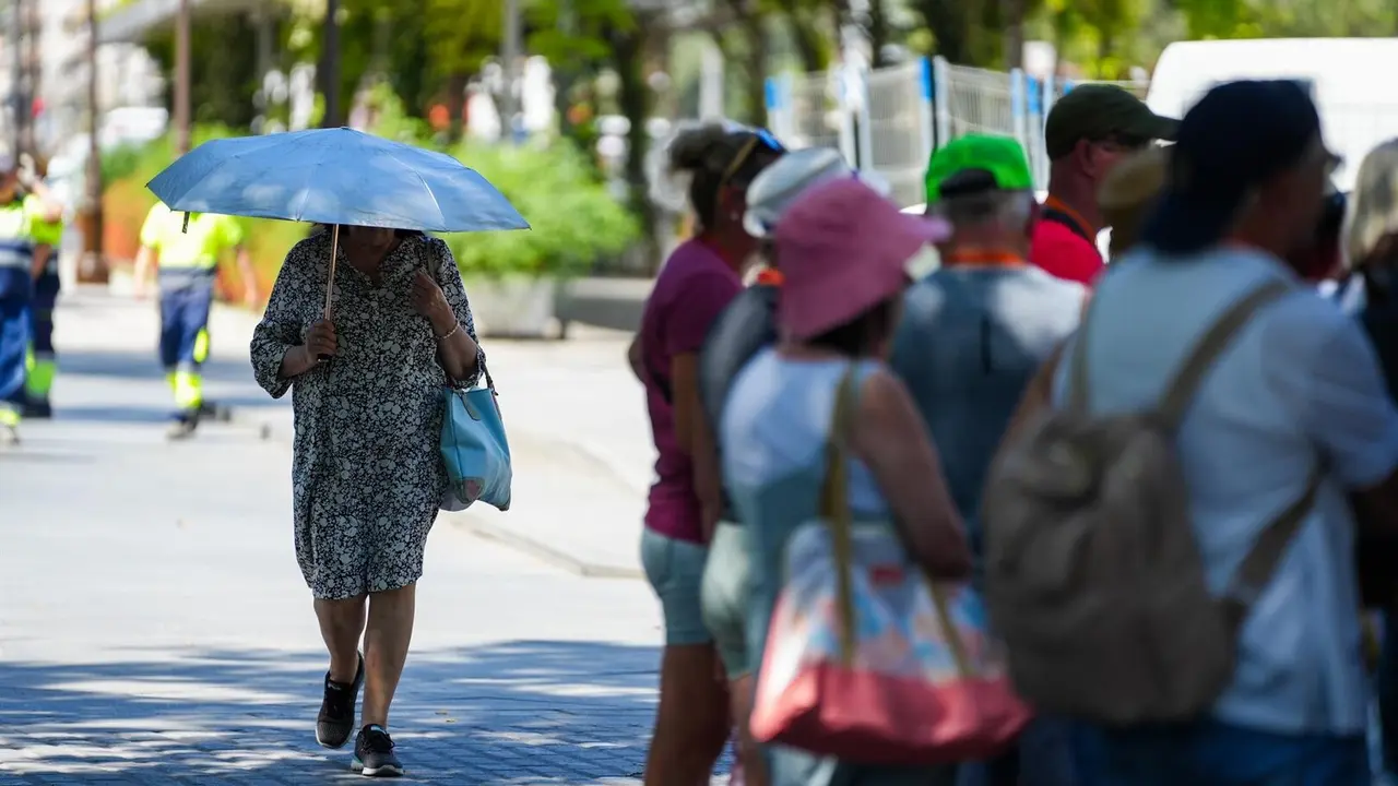 Una mujer con una sombrilla junto a un grupo de turistas. /  Europa Press