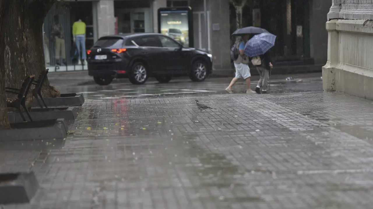 Dos personas caminan bajo la lluvia, en Huesca, Aragón (España). / EP