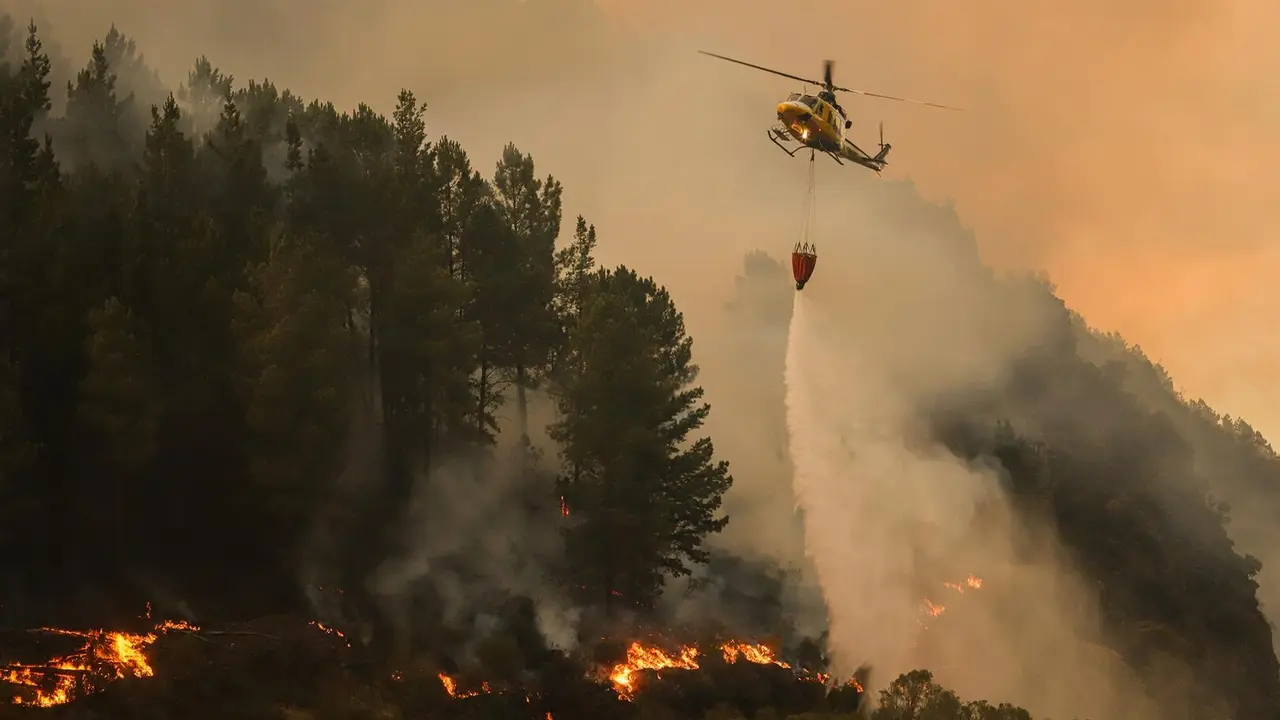 Un helic&oacute;ptero suelta agua sobre el fuego, a 26 de agosto de 2025, en Covas, Lugo. / EP