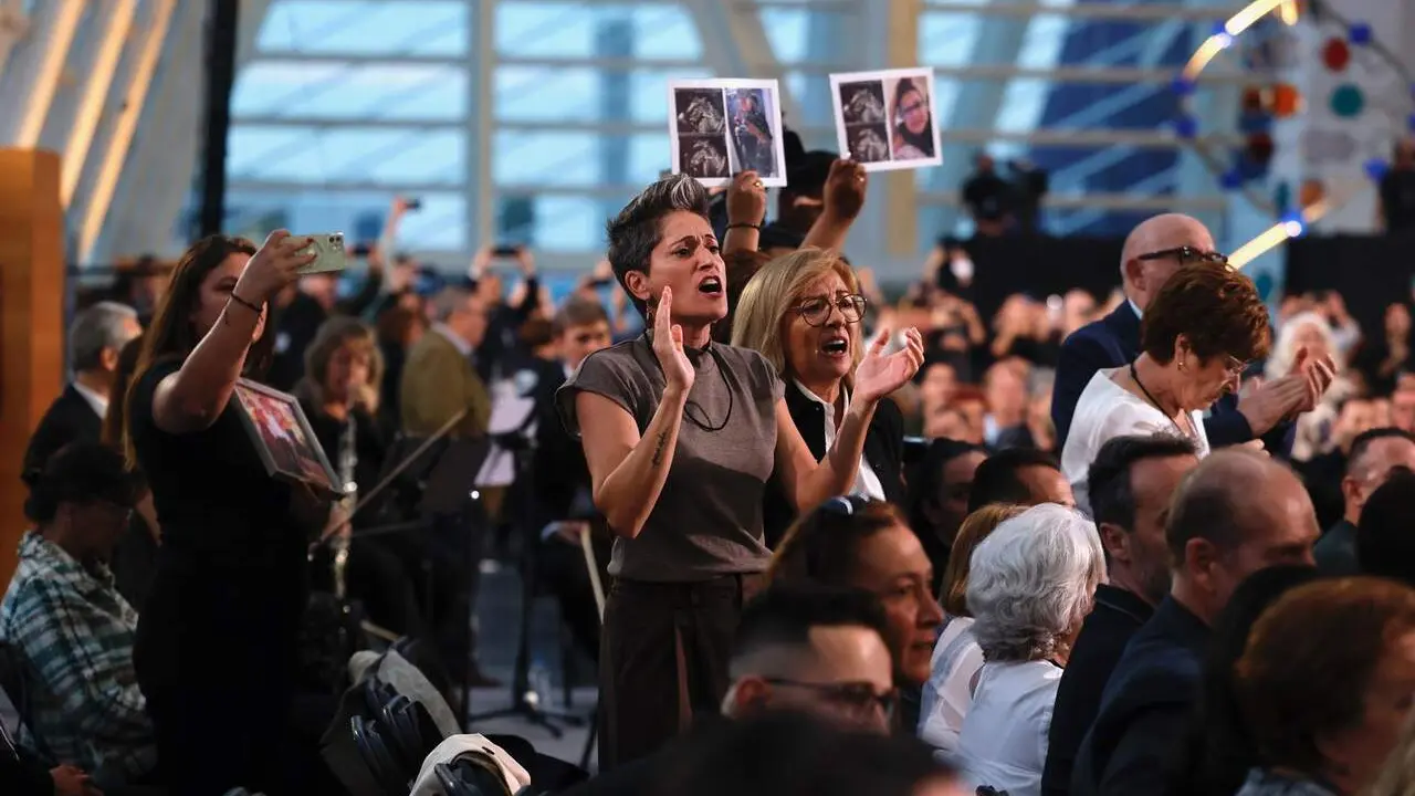 Familiares de v&iacute;ctimas de la dana, con fotos de sus allegados, protestan antes del inicio del funeral de Estado. / EP