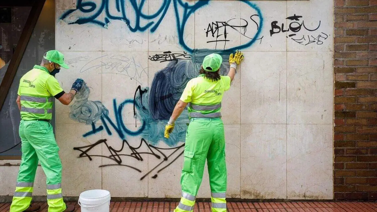 Dos t&eacute;cnicos de limpieza borrando grafitis de una pared ./ Ayuntamiento de Zaragoza