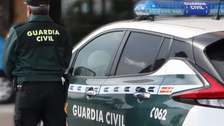 Un agente de la Guardia Civil, de espaldas, junto a un veh&iacute;culo oficial. - GUARDIA CIVIL