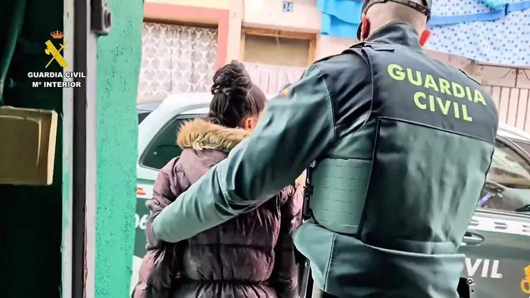 UN agente de la Guardia Civil se lleva a una de las detenidas en la operaci&oacute;n 'Corviza' en la que se han arrestado a 14 personas de un clan familiar por okupar una casa de un anciano de 90 a&ntilde;os incapacitado y estafarle m&aacute;s de 14.000 euros ./ Guardia Civil